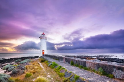 The enigmatic light house of Port Fairy, situated in one of Victoria’s prettiest towns, looms large against a dramatic sunrise on the water’s edge.